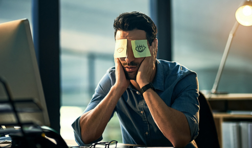 uomo in ufficio con occhi stanchi dopo aver usato il computer